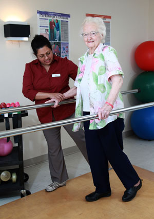 physiotherapist assists an elderly woman in exercises